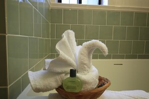 A bathroom with green tiles, a white towel, and a bottle of shampoo. - Radio City Apartments (New York)