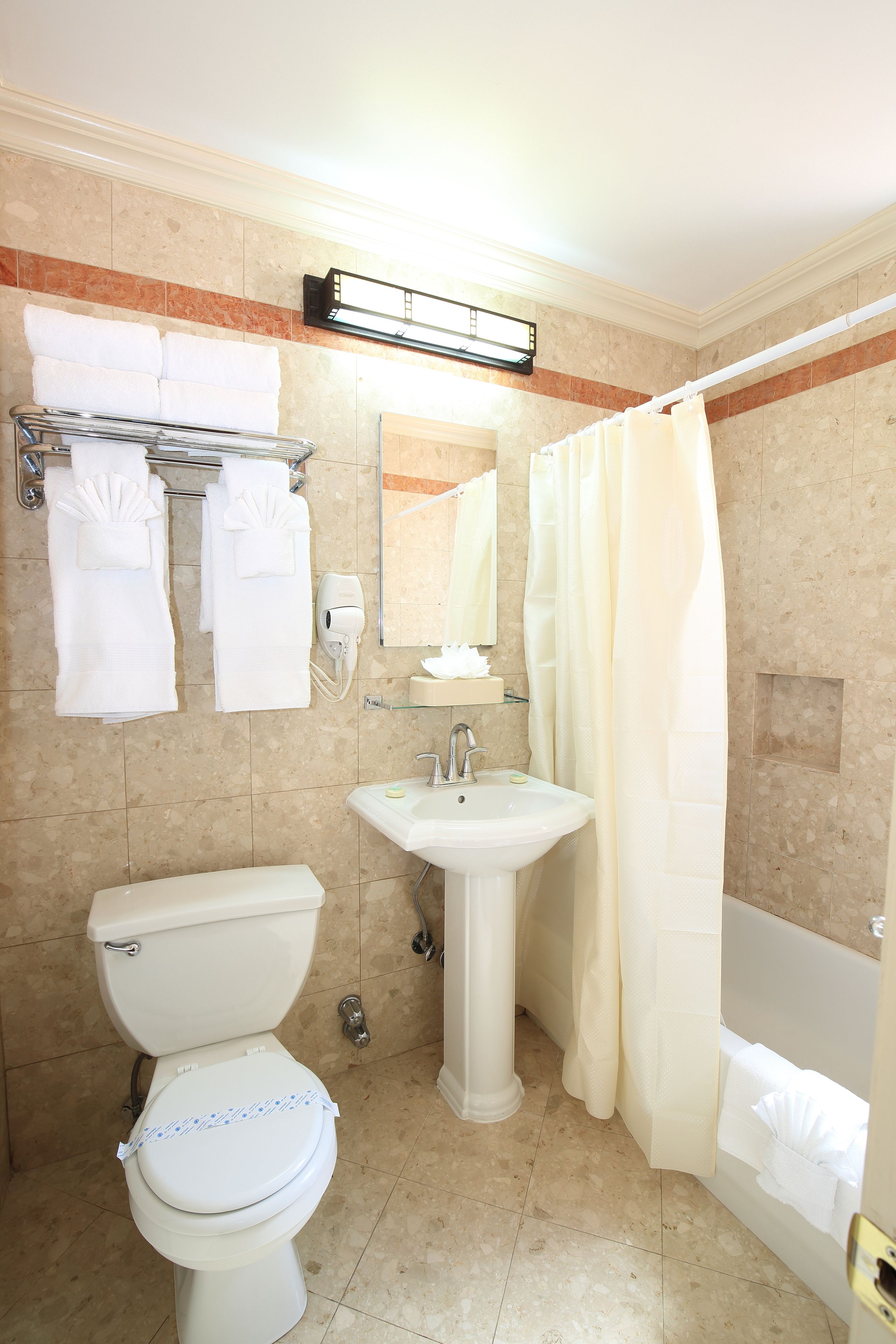 Un baño con inodoro, lavamanos y cortina de ducha.