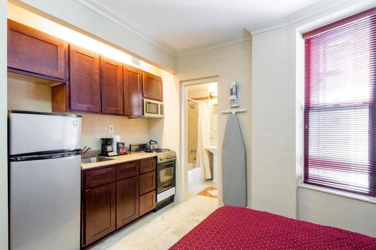 A compact kitchen with wooden cabinets, a refrigerator, microwave, and stove.