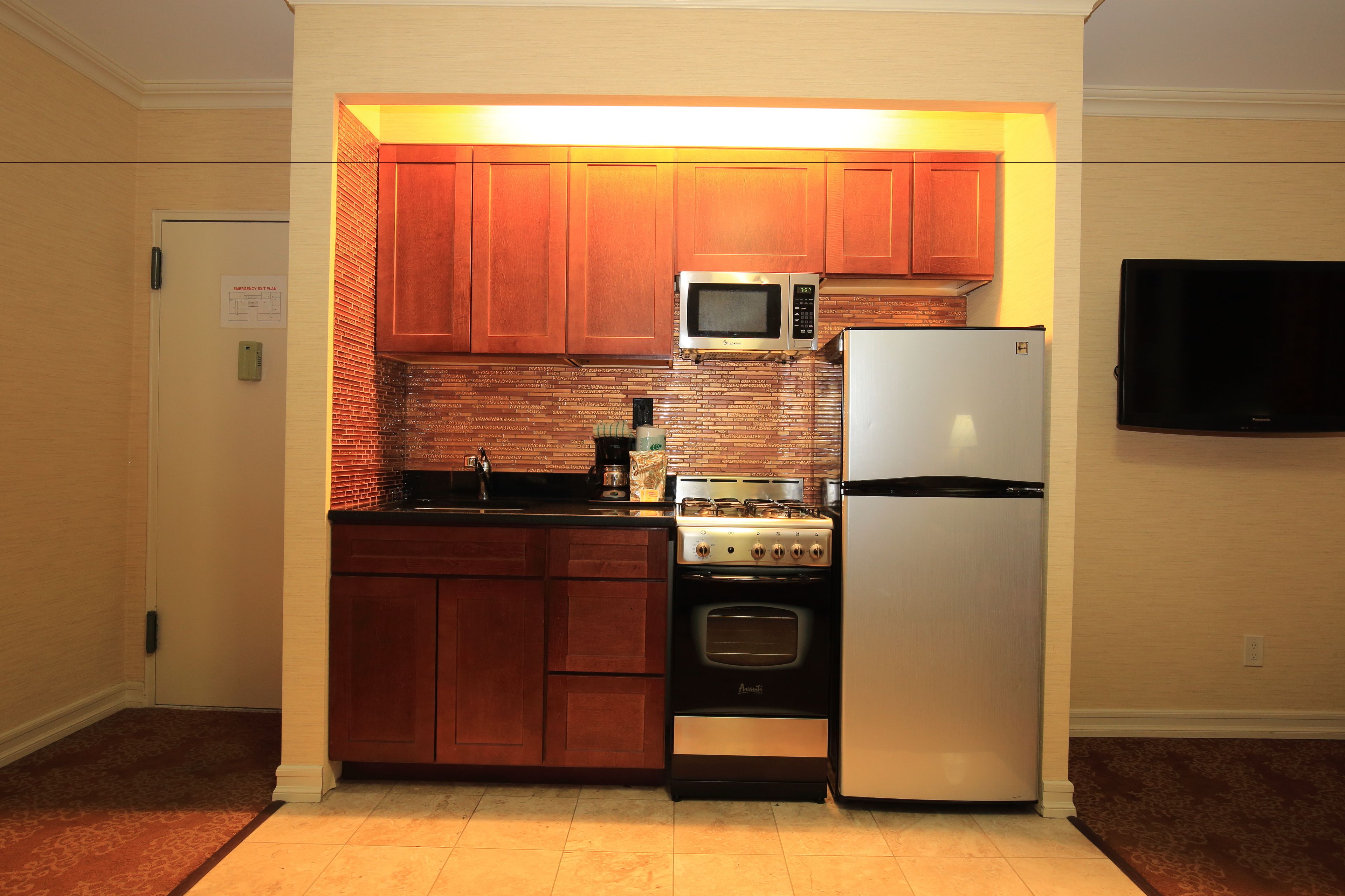 A compact kitchen with wooden cabinets, a microwave, a stove, and a refrigerator.