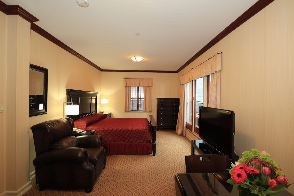 A hotel room with a bed, a TV, a desk, a chair, and a lamp.