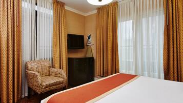 A hotel room with a large bed, a chair, a flat-screen TV, and a dresser.