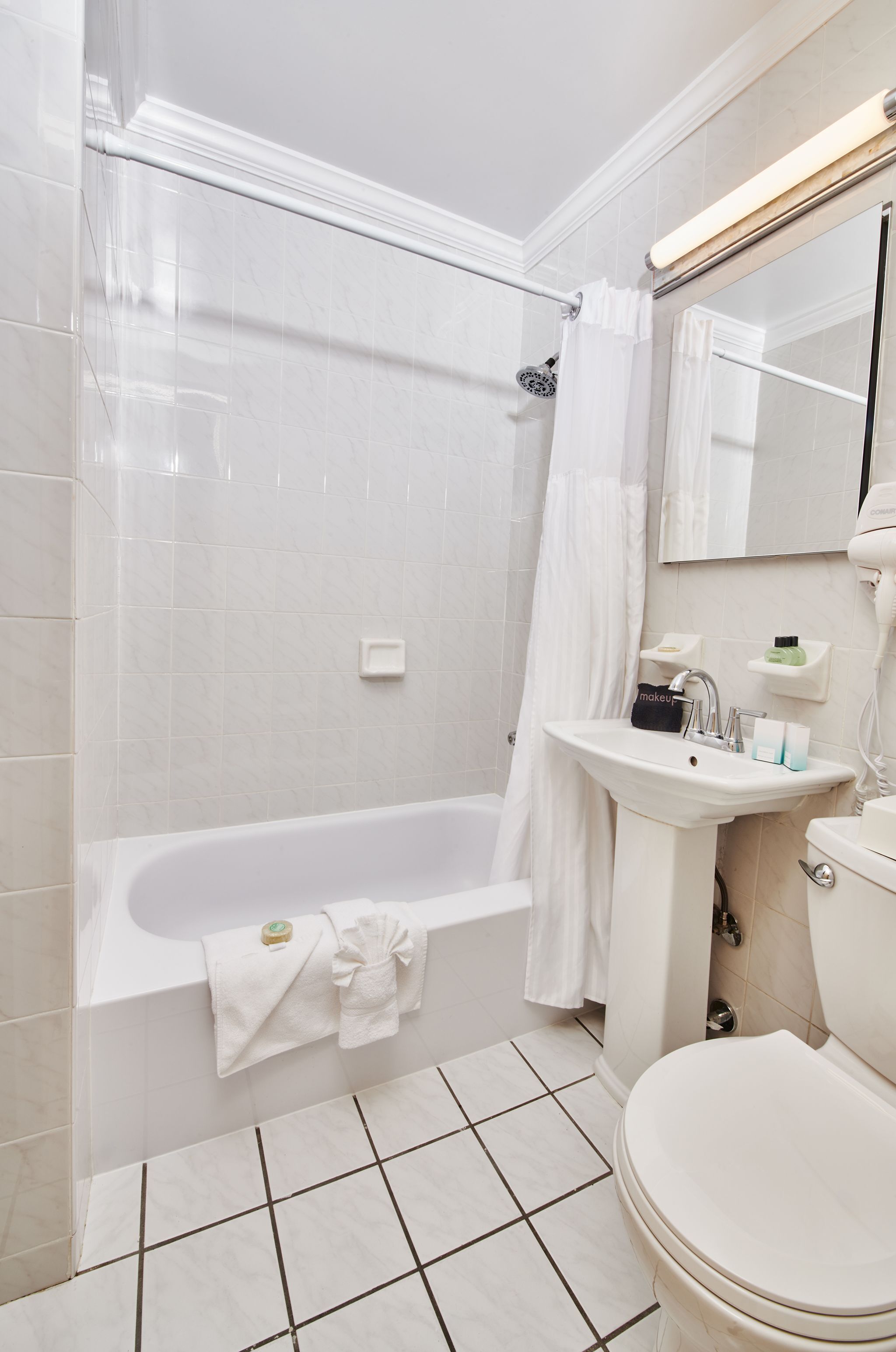 A bathroom with a bathtub, a sink, a toilet, and a mirror.