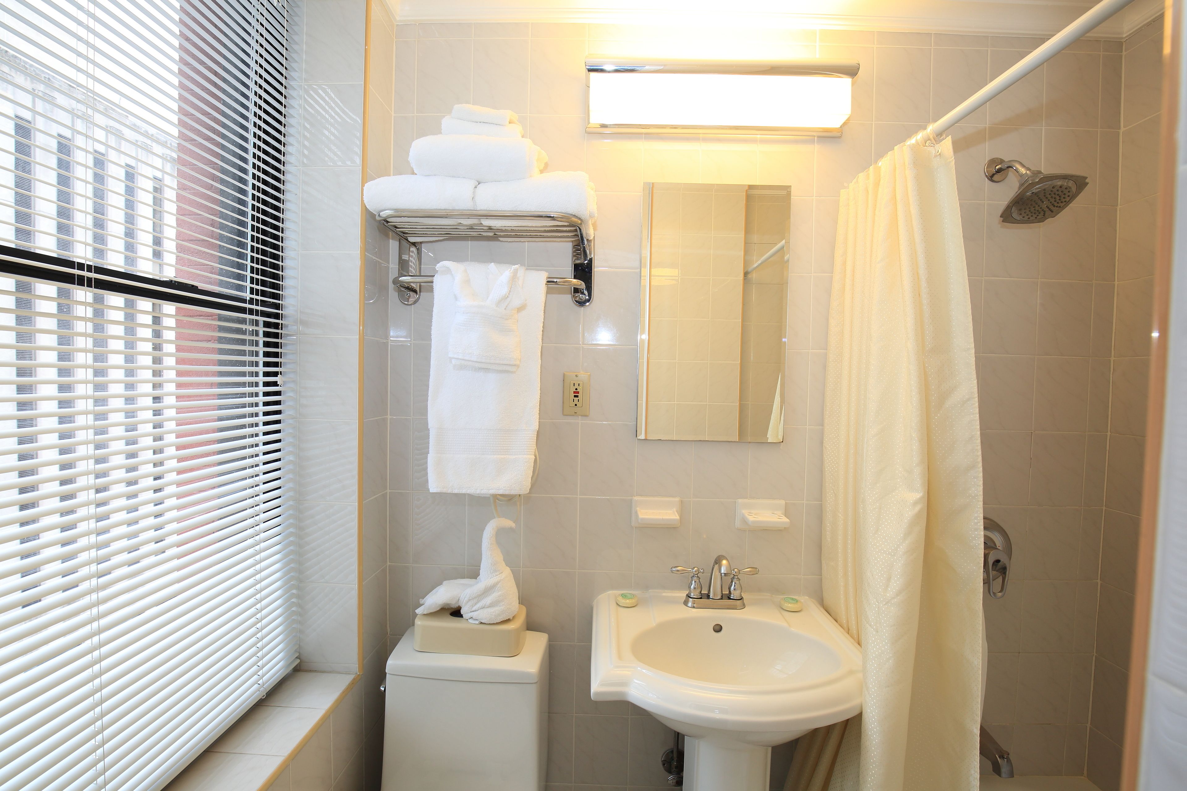 A bathroom with a sink, mirror, towel rack, and shower curtain.
