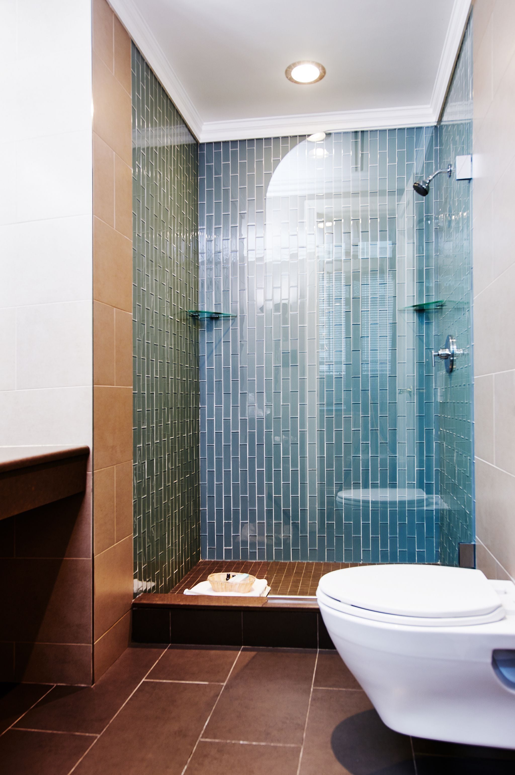 A bathroom with a glass-enclosed shower, a white toilet, and a tiled floor.