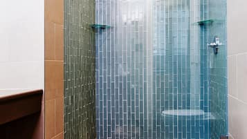 A bathroom with a glass-enclosed shower, a white toilet, and a tiled floor.