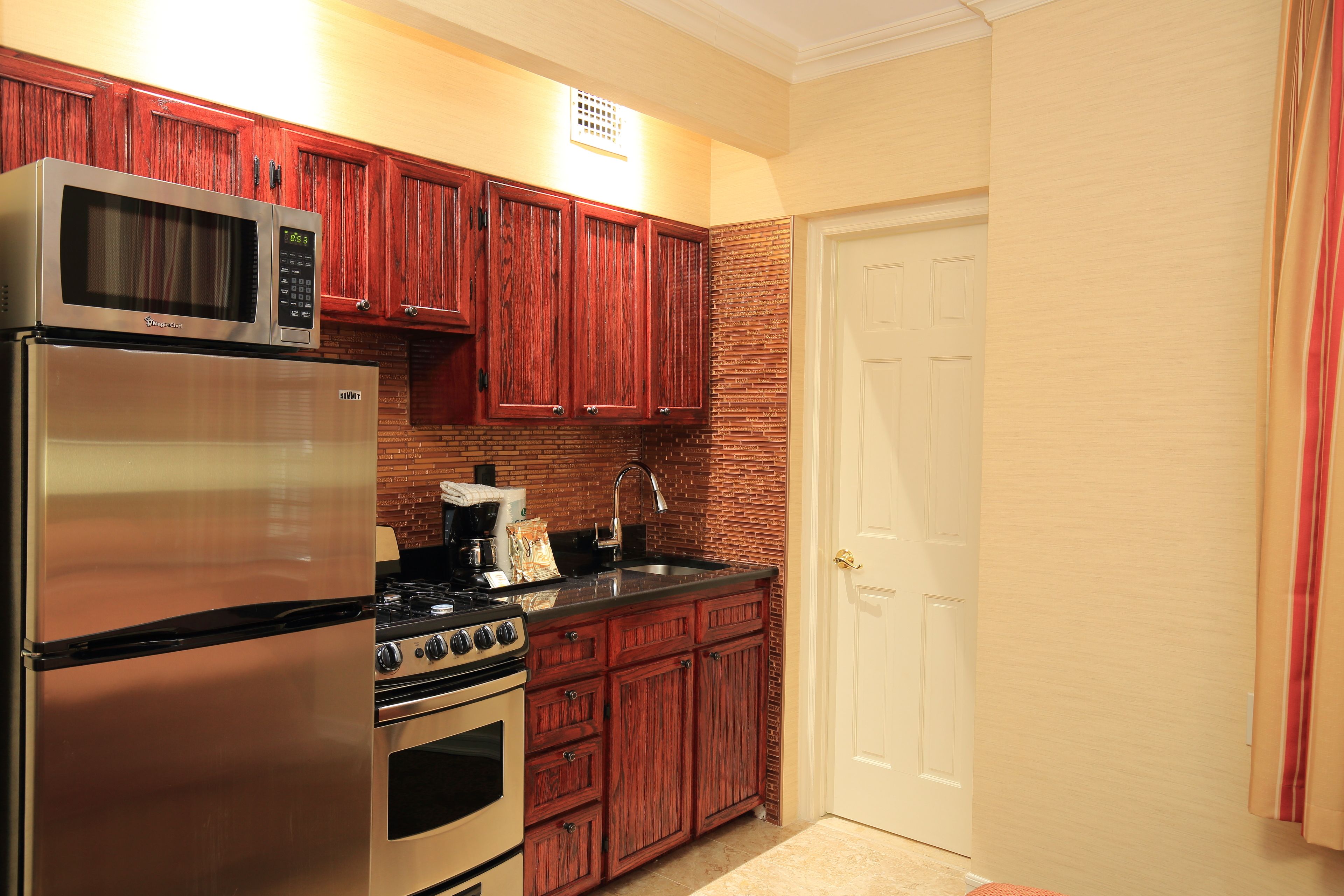 A kitchen with wooden cabinets, stainless steel appliances, and a white door.