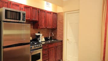 A kitchen with wooden cabinets, stainless steel appliances, and a white door.