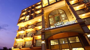 A multi-story hotel with balconies and a prominent arched entrance. - Victoria Nimman Hotel (Chiang Mai)