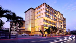 A multi-story hotel with balconies, palm trees, and a well-lit facade. - Victoria Nimman Hotel (Chiang Mai)