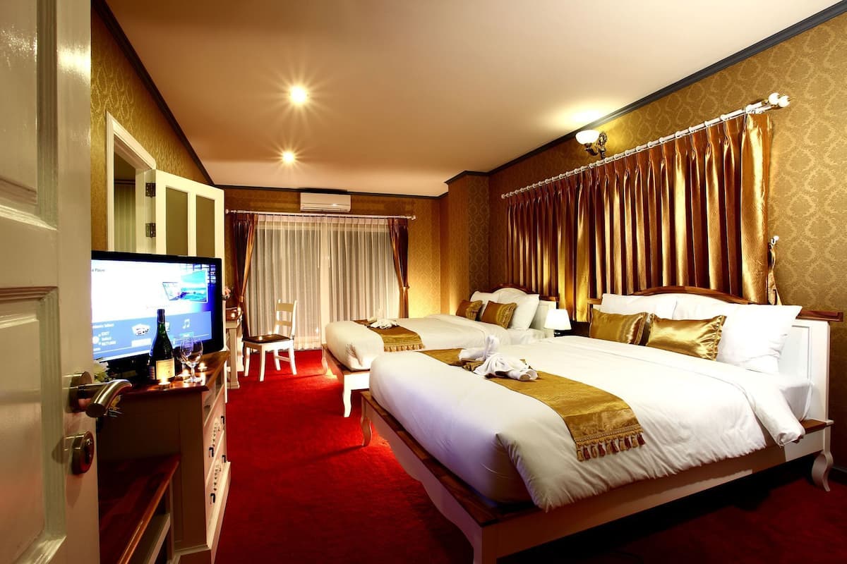 A hotel room with a large bed, a desk with a television, and a red carpet.