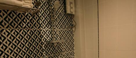 A bathroom with a patterned wall, a toilet, a shower, and a glass partition.
