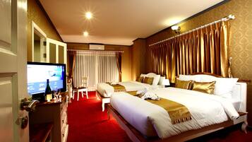 A hotel room with a large bed, two bedside tables, a TV, and a red carpet.