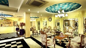 A hotel lobby with a checkered floor, ornate chairs, a wooden table, and a large chandelier. - Victoria Nimman Hotel (Chiang Mai)