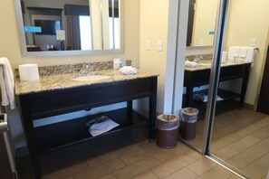 A bathroom with a granite countertop sink, a mirror, a towel rack, and two trash bins. - Hampton Inn & Suites Salinas (Salinas)
