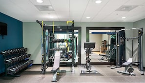 Un gimnasio con diversos equipos de ejercicio, como mancuernas, kettlebells y máquinas de pesas.