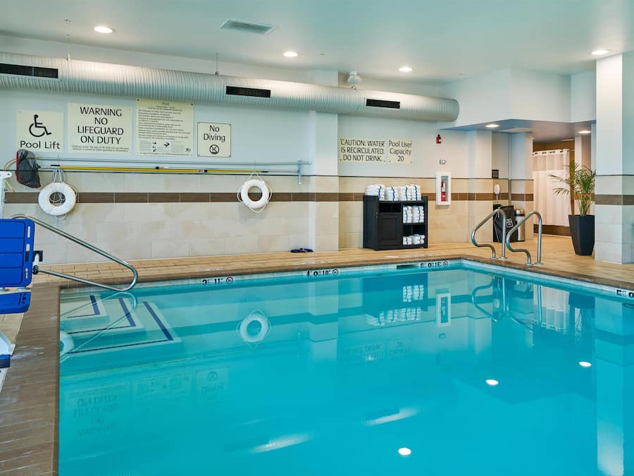 An indoor swimming pool with a pool lift, no diving sign, and a caution about water recirculation.