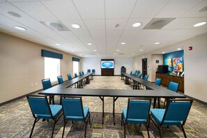A conference room with a long table, blue chairs, a projector screen, and a colorful artwork on the wall. - Hampton Inn & Suites Salinas (Salinas)