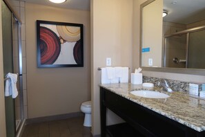 A bathroom with a marble sink, a toilet, a towel rack, and a framed abstract painting on the wall. - Hampton Inn & Suites Salinas (Salinas)