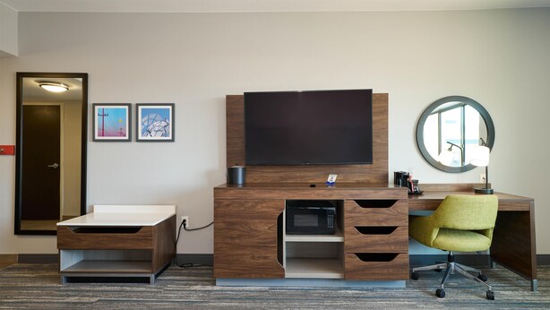 A hotel room with a flat-screen TV, a desk with a chair, a coffee maker, and a round mirror. - Hampton Inn & Suites Salinas (Salinas)