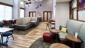 A modern hotel lobby with a seating area, tables, and a patterned carpet. - Hampton Inn & Suites Salinas (Salinas)