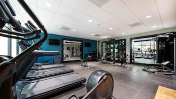 Un gimnasio con cintas de correr, bicicletas estáticas y máquinas de pesas.