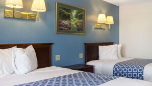 Une chambre d’hôtel avec deux lits, un tableau au mur et deux lampes fixées au mur.