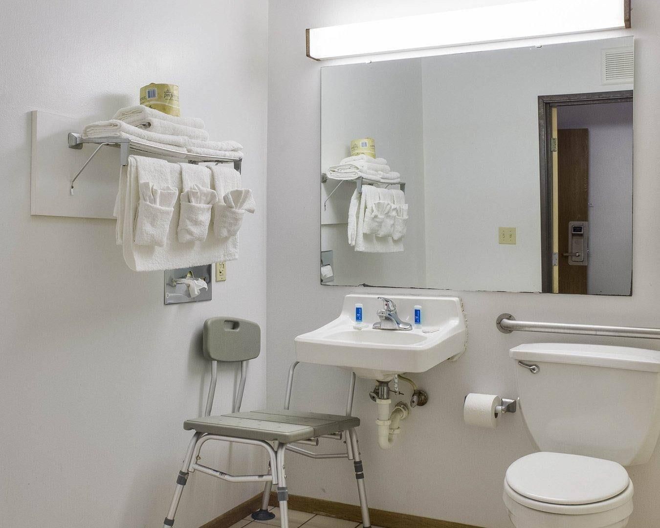 Une salle de bain d’hôtel standard, équipée d’un lavabo, de toilettes et d’un miroir.
