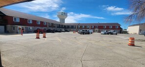 A parking lot with several vehicles, a building with a water tower, and a clear sky. - Rodeway Inn West Fargo Main Ave. (West Fargo)