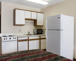 Cocina compacta con alacenas blancas, microondas, refrigerador y estufa.