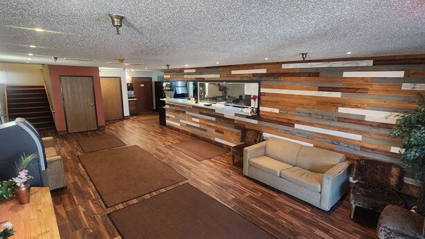 Un vaste espace de vie doté d’un plancher en bois, d’un canapé, d’une table basse et d’un coin cuisine comprenant un réfrigérateur et un évier.