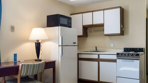 Une cuisine compacte équipée d’un réfrigérateur, d’un four à micro-ondes, d’une cuisinière et d’un petit coin repas avec une chaise et une table.
