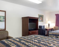 Una habitación de hotel con dos camas, televisión, escritorio con lámpara y microondas.