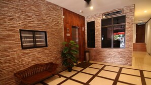 A lobby with a wooden bench, a potted plant, a tiled floor, and a reception desk. - AG Hotel Penang (George Town)