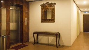 An elevator, a mirror, and a console table in a hallway. - AG Hotel Penang (George Town)