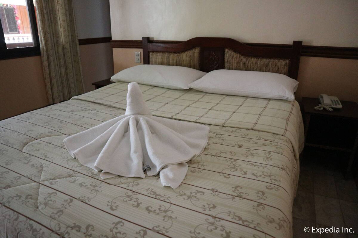 Una cama bien hecha con una toalla doblada encima.