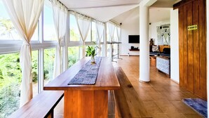 A spacious room with large windows, a wooden table, a TV, and a "No Smoking" sign.