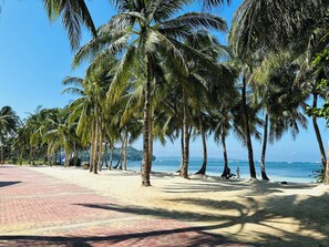 A beach with palm trees and a paved walkway. - Aissatou Beach Resort (Boracay Island)