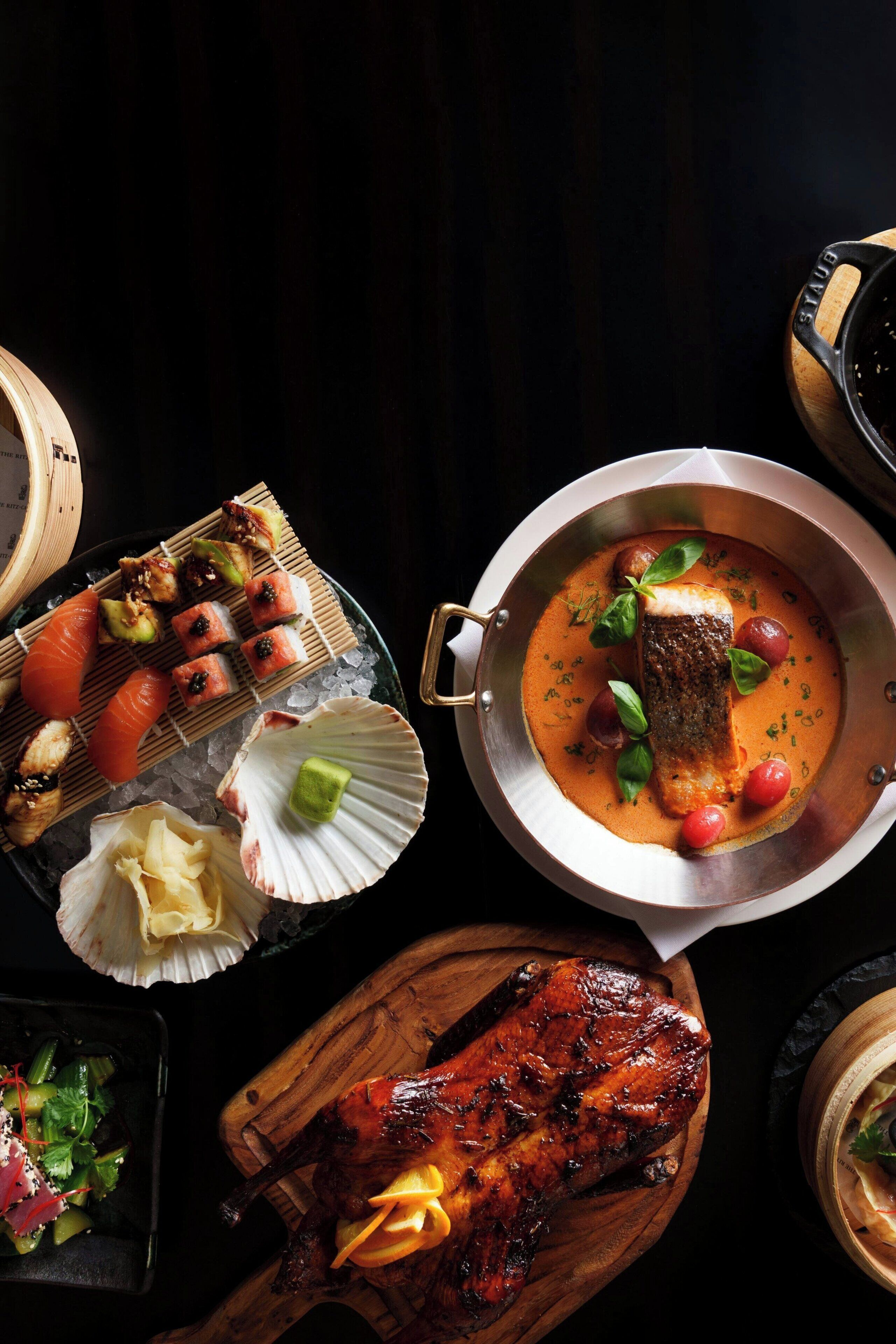 Variedad de platos, incluyendo sushi, un pescado en salsa cremosa y carne a la parrilla.