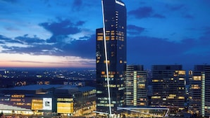 A high-rise building with a modern design, featuring a prominent vertical light strip and a large illuminated sign.