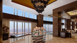 A spacious lobby with a large window offering a city view, a modern chandelier, and a reception desk. - The Ritz-Carlton, Almaty (Almaty)