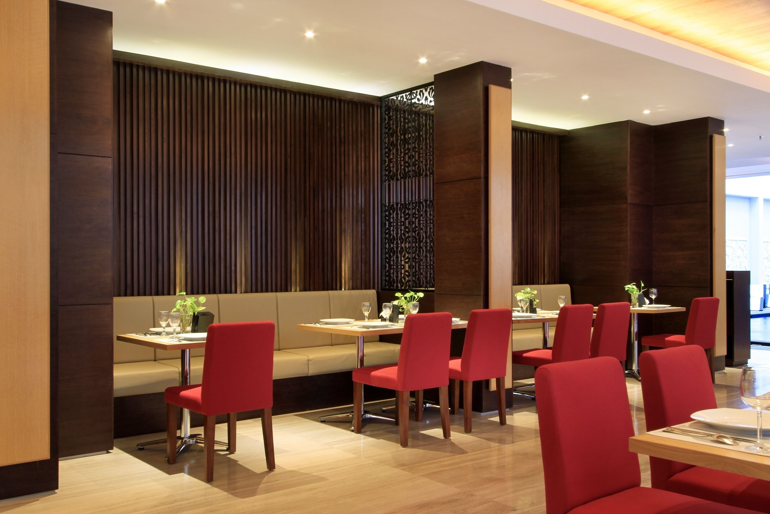 Un restaurant moderne avec des boiseries, des chaises à revêtement rouge et une ambiance chaleureuse.