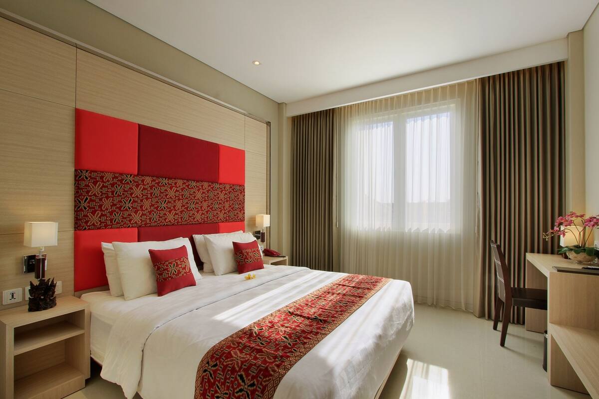 A hotel room with a large bed, a desk, and a chair.