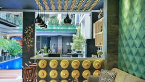 Un vestíbulo moderno con una zona de bar, asientos y vistas a una piscina.