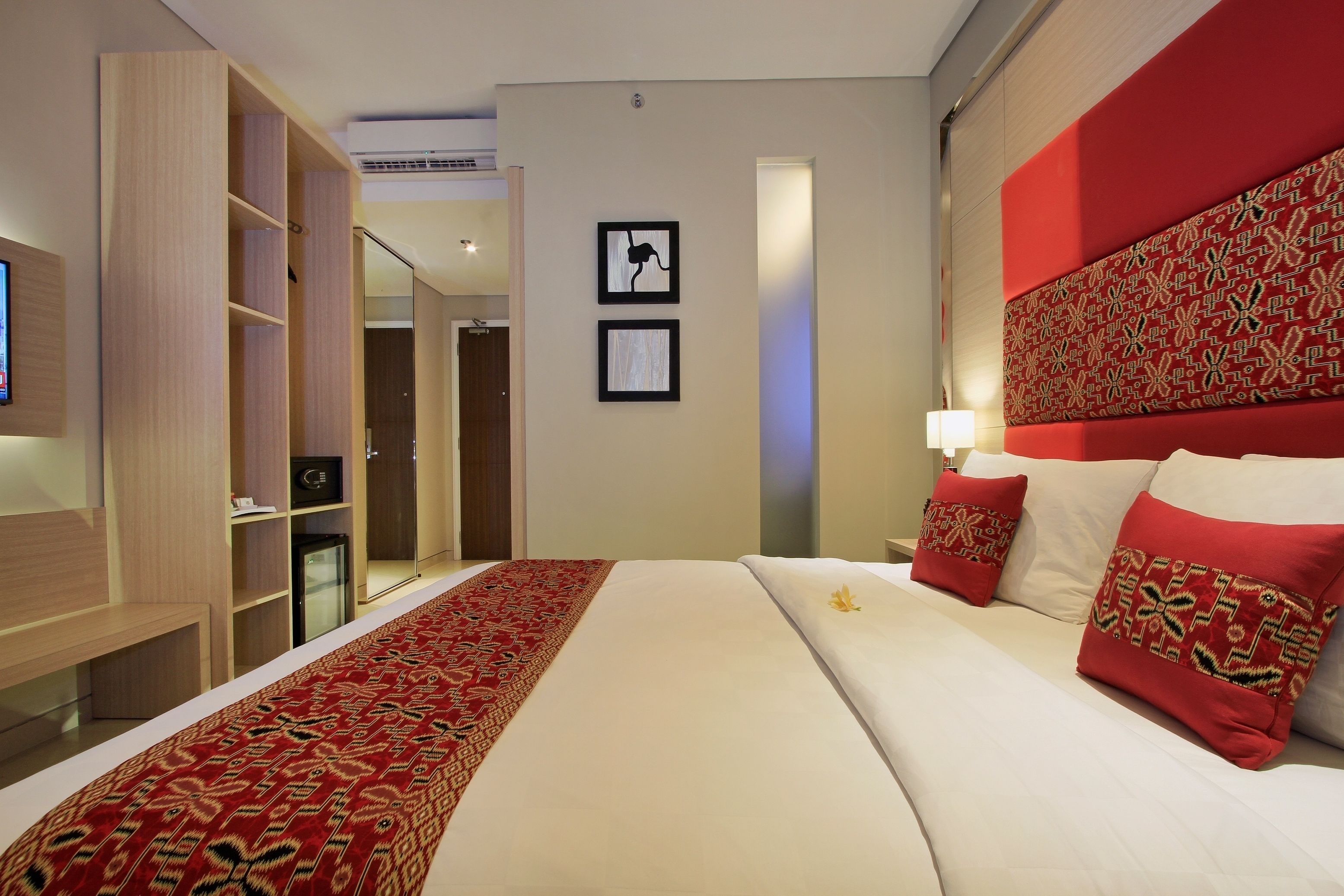 A hotel room with a large bed, a wooden wardrobe, a desk, and a television.