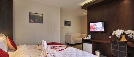 Habitación de hotel con cama, televisión, escritorio y silla.