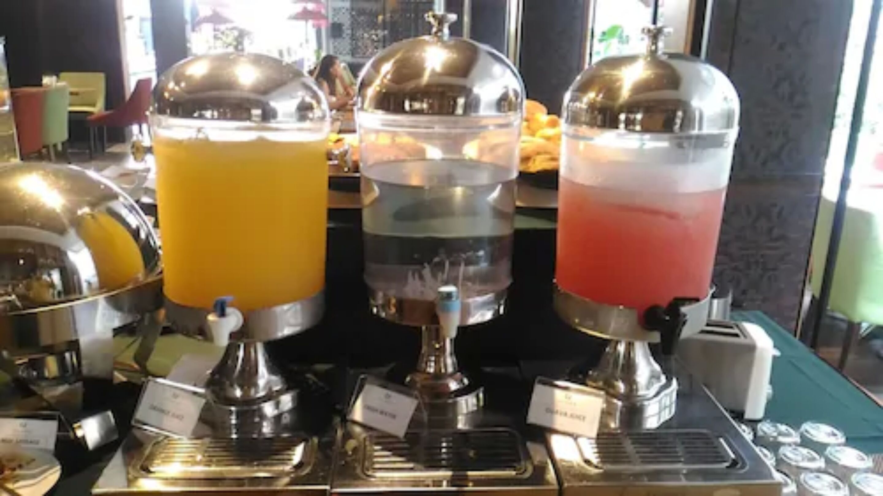 A buffet with three beverage dispensers filled with different drinks.