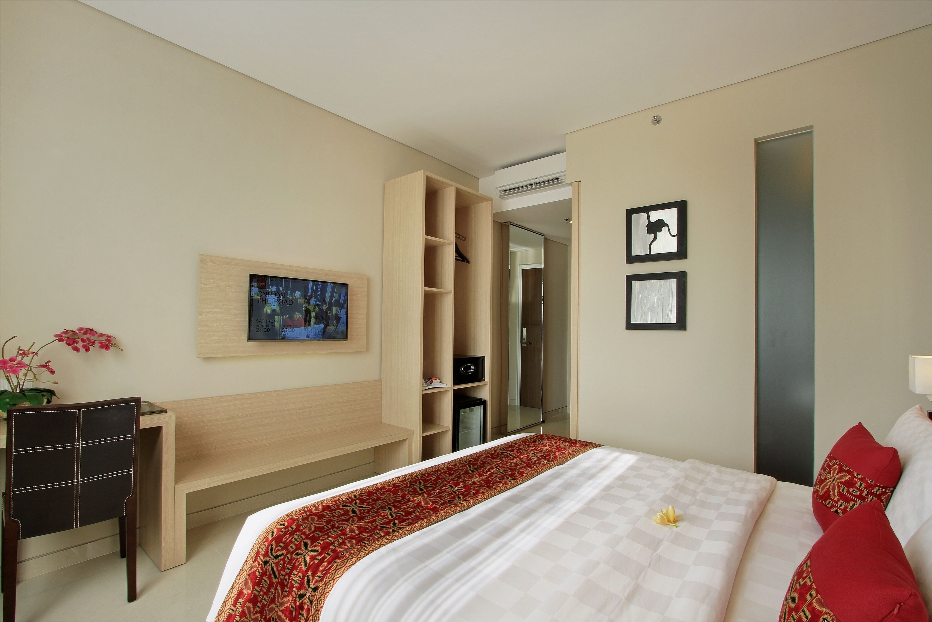 Habitación de hotel con cama, escritorio, armario, televisor y ducha.