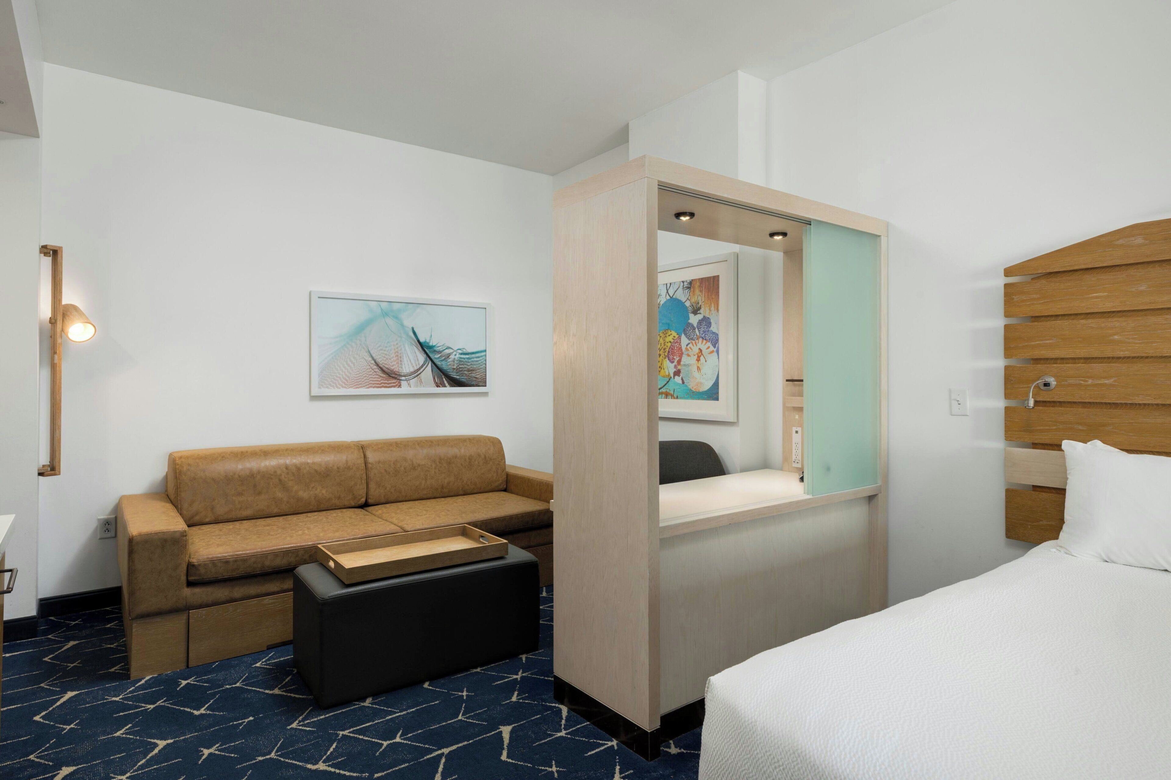 Ein Hotelzimmer mit Bett, Sofa, Schreibtisch und Spiegel.