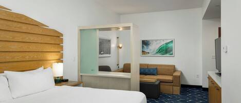 Ein Hotelzimmer mit Bett, Schreibtisch, Sessel, Fernseher und einem Bild an der Wand.